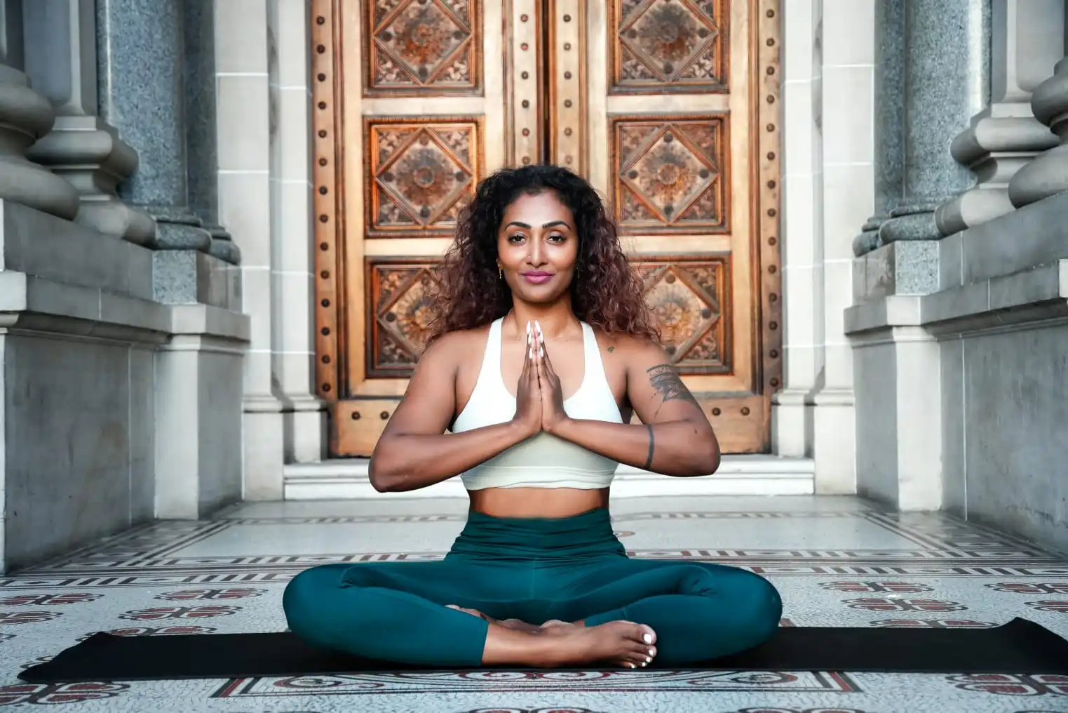 Dr. Kavitha Mohan in yoga pose behind aum yog studio logo.